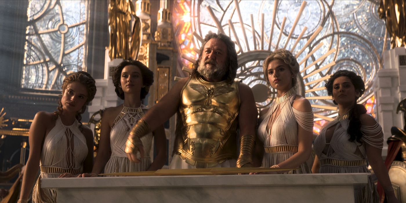 Russell Crowe in character as Zeus in Thor Love and Thunder wearing God-like golden armor and flanked by women in gowns