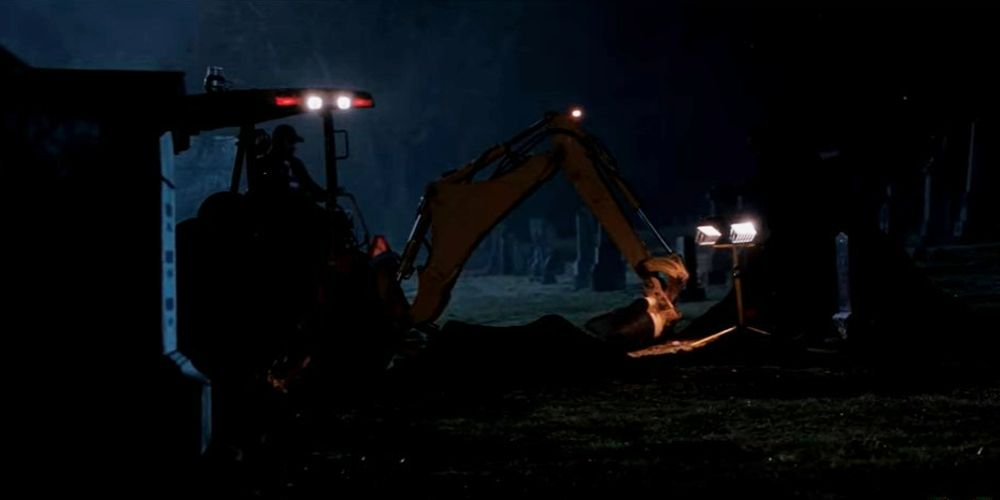 Image of Bobby operating an excavator to dig a grave while Rufus watches