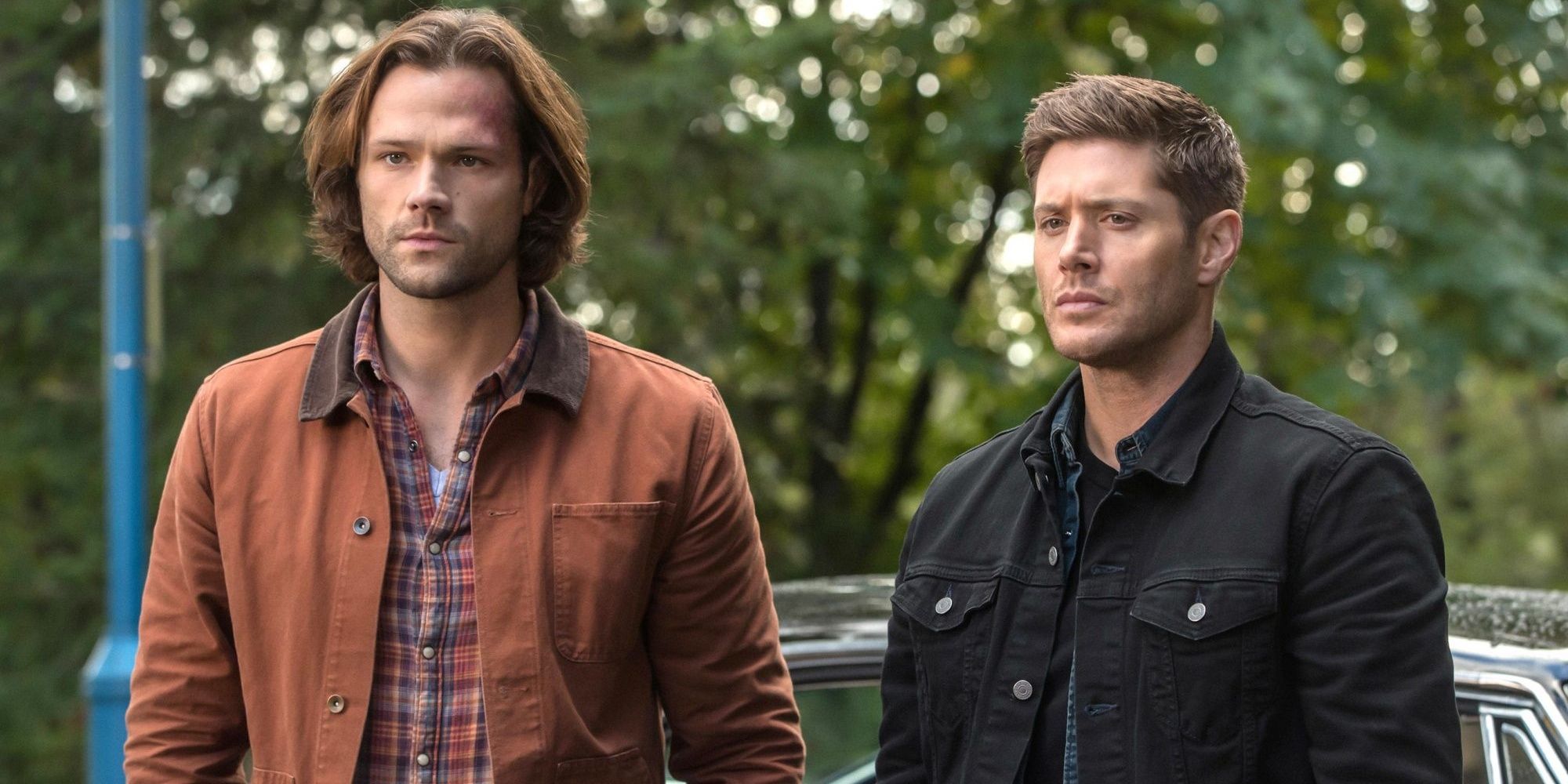 Sam and Dean Winchester standing in front of their car