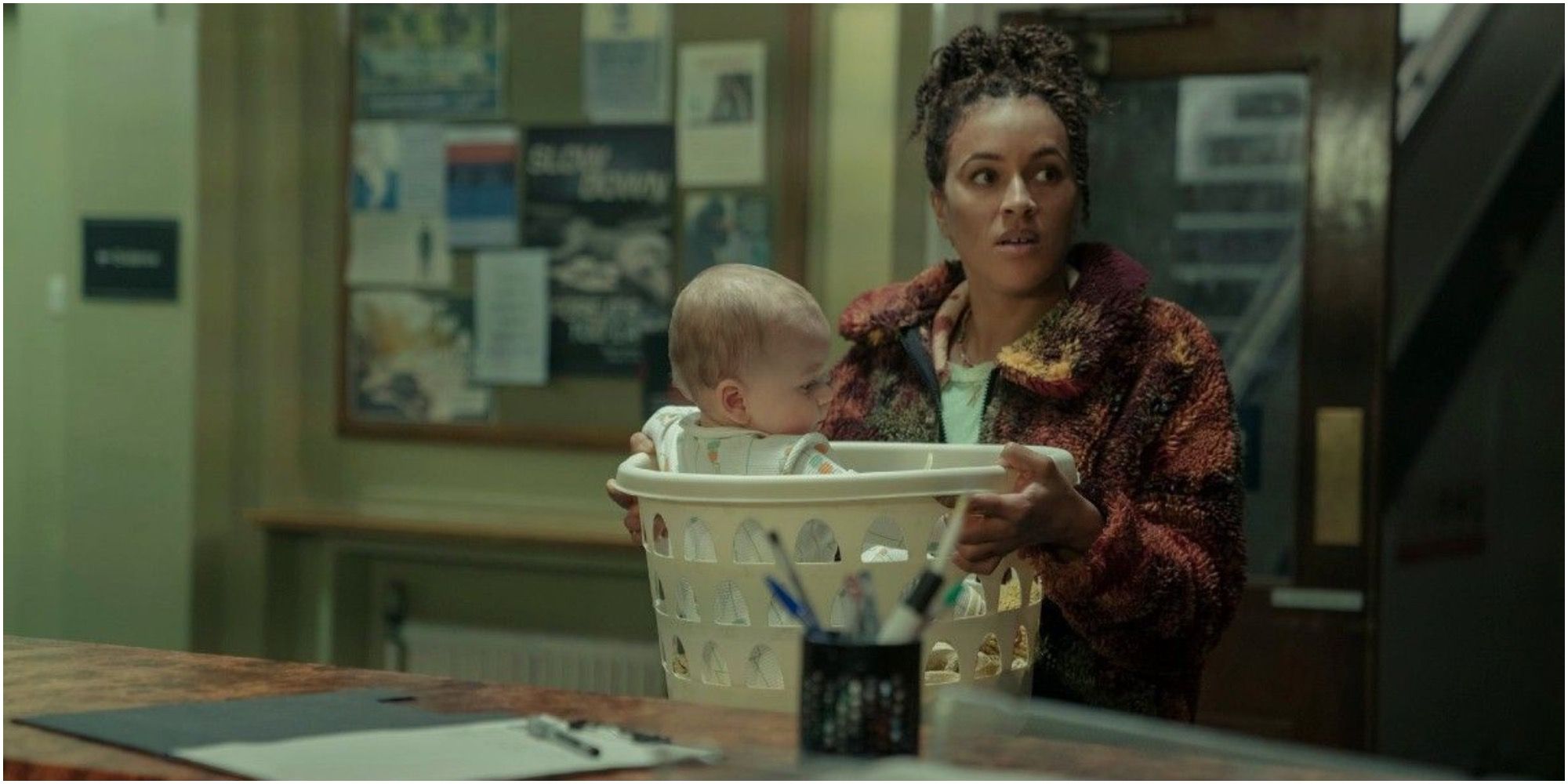 Image of Tash with the baby in a clothes hamper at the police station In The Baby