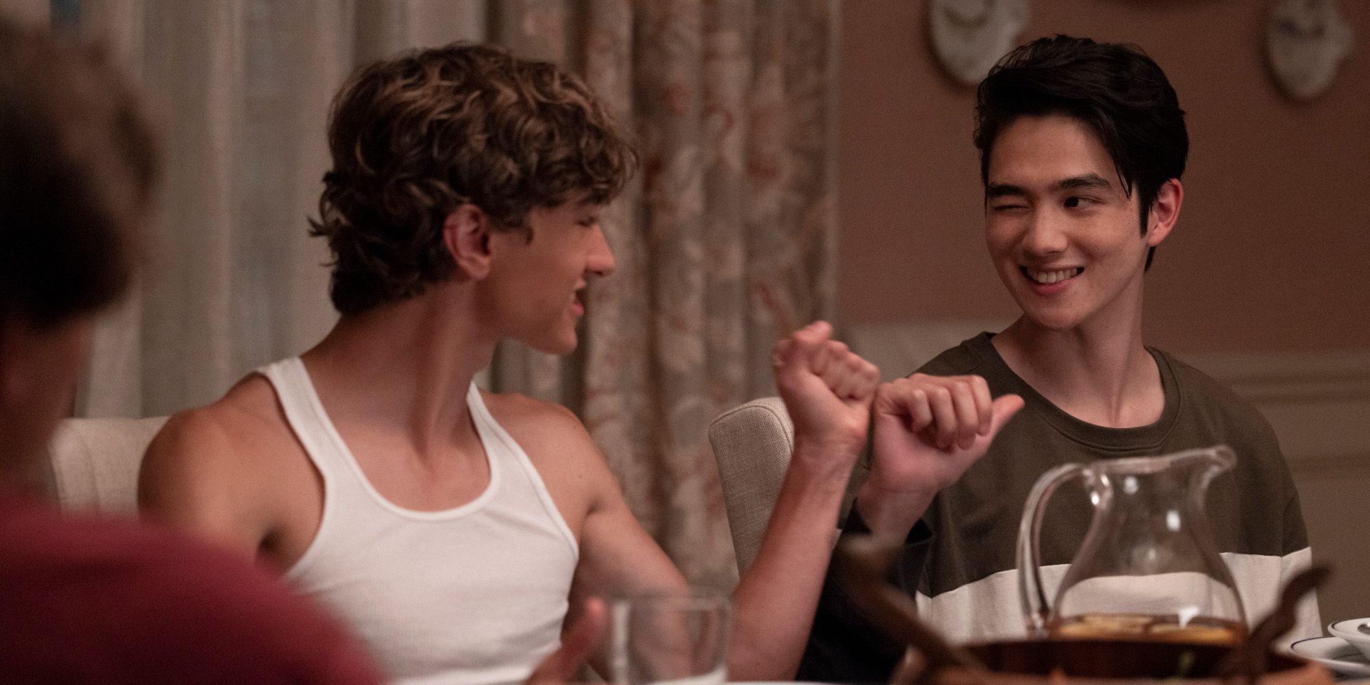 Gavin Casalegno as Jeremiah and Sean Kaufman as Steven fist-bumping at the dinner table in The Summer I Turned Pretty.