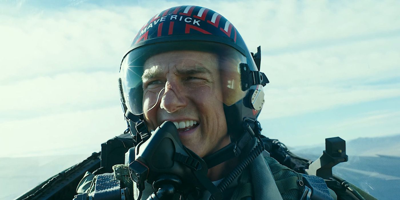 Tom Cruise no personagem como Maverick em Top Gun Maverick pilotando um jato em um capacete com máscara de oxigênio cobrindo parcialmente o rosto