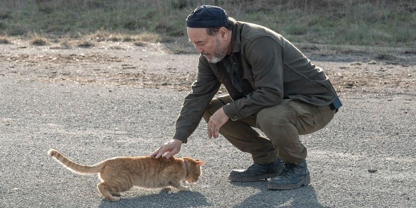 Daniel from Fear the Walking Dead leaning down and petting Skidmark the cat.