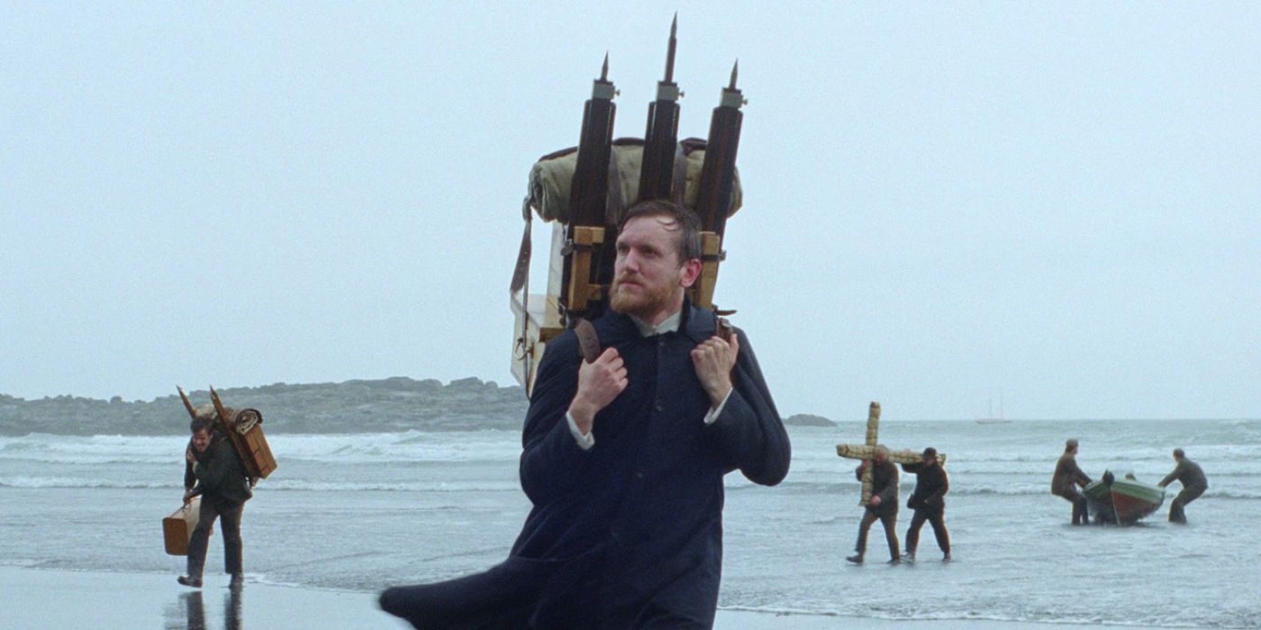 A still from Godland showing the priest walking across a beach