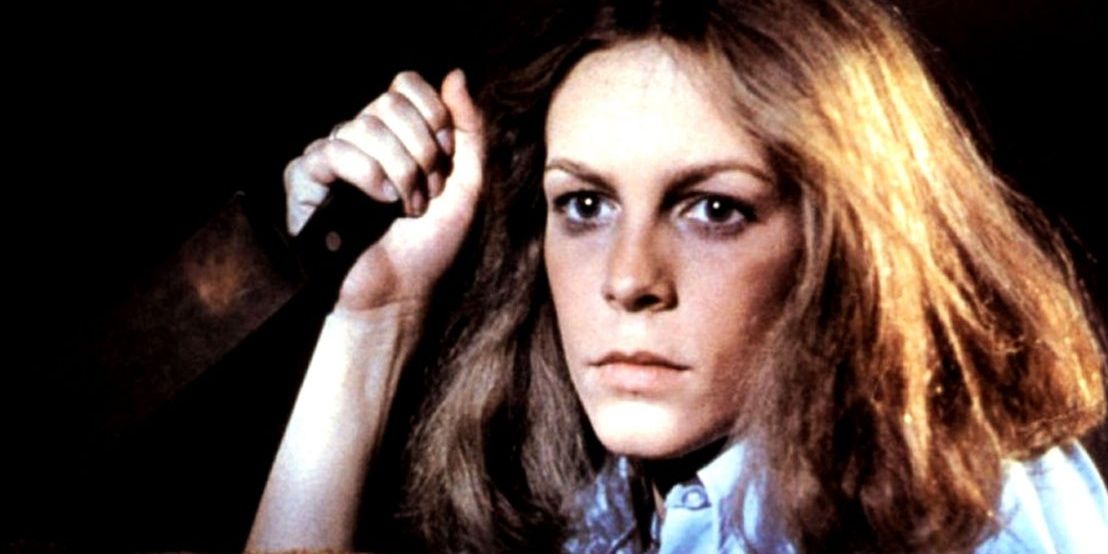 Laurie Strode looking over her couch with a knife in hand