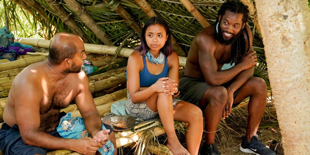 Survivor contestants sit in a hut and talk