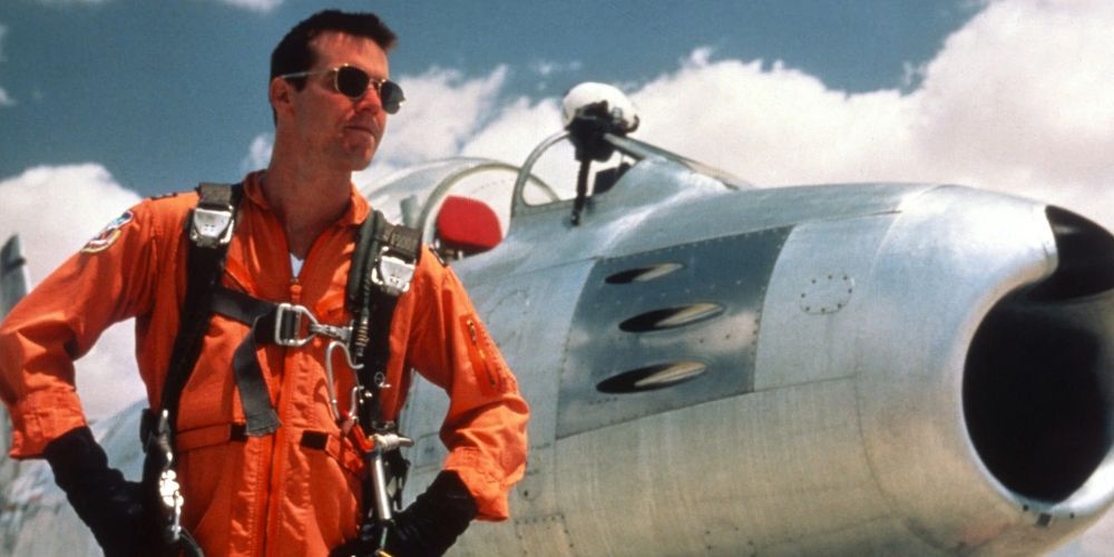 Chuck stands by an airplane in an orange jumper in The Right Stuff