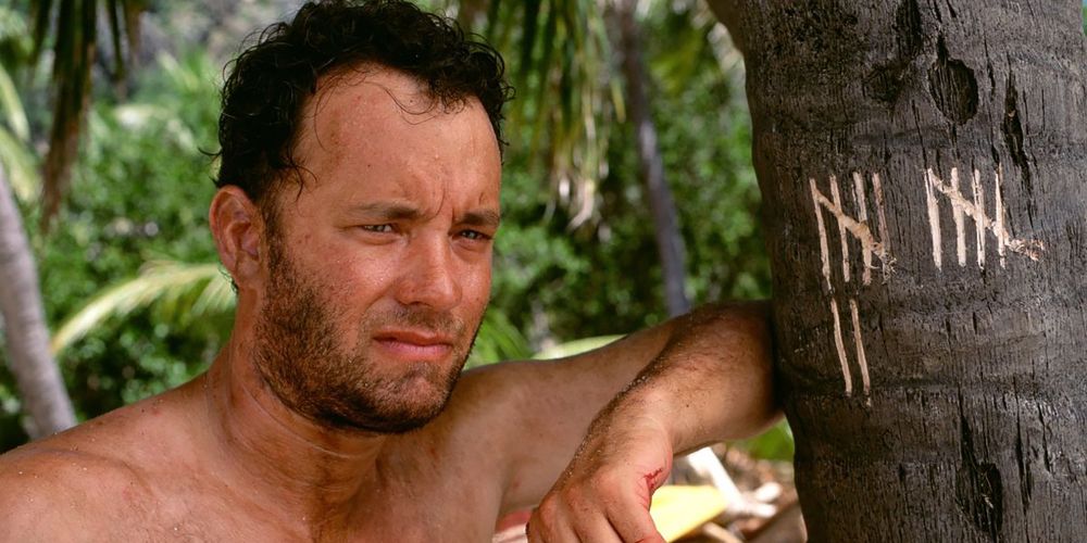 Chuck stands by a tree with a tally count in Cast Away