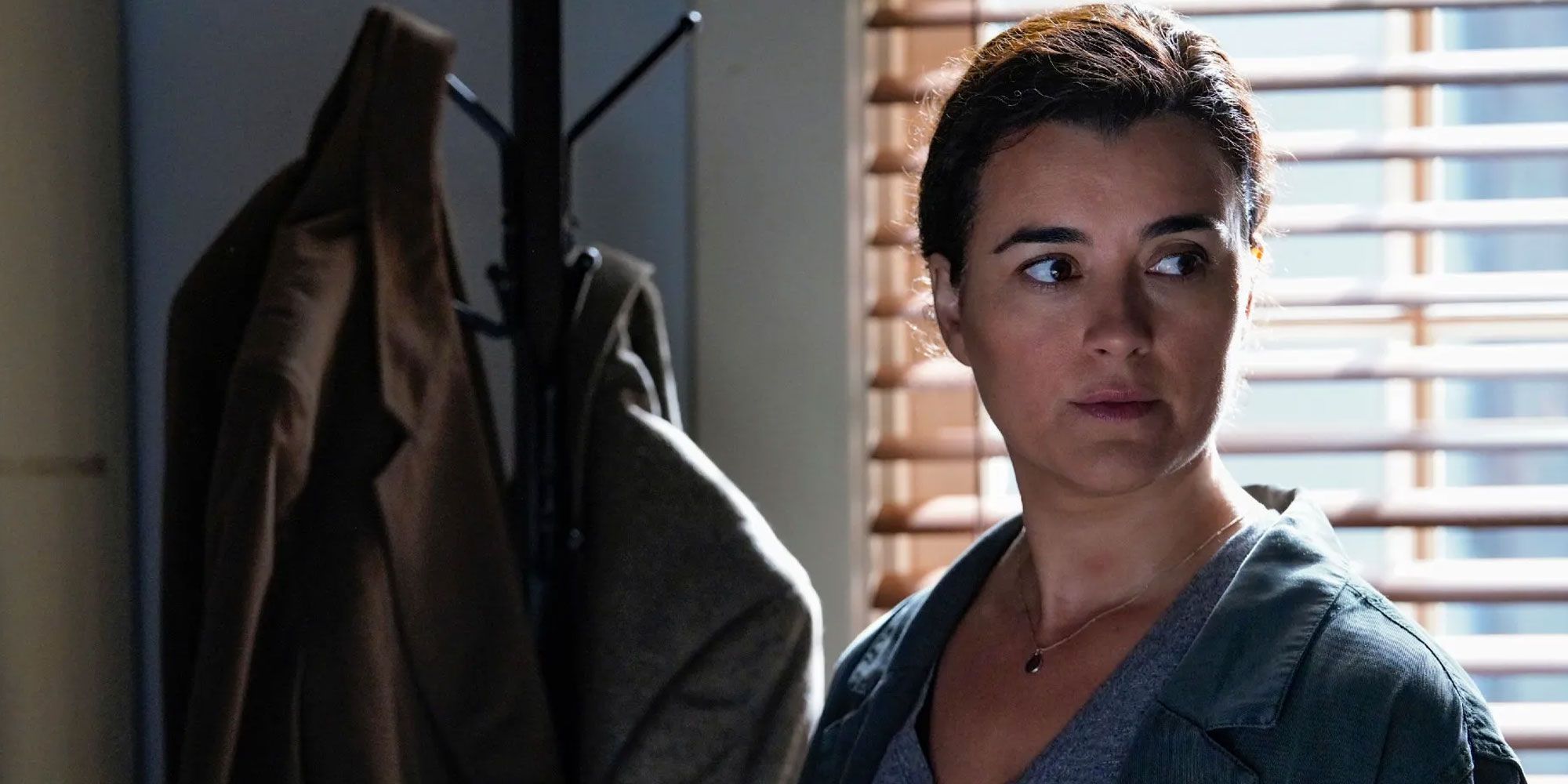 Ziva David stands in front of a coat rack in NCIS.