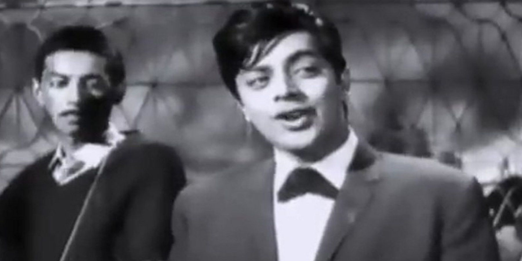 A man smiling and looking sideways in a still from the music video for Ko Ko Korina Cropped