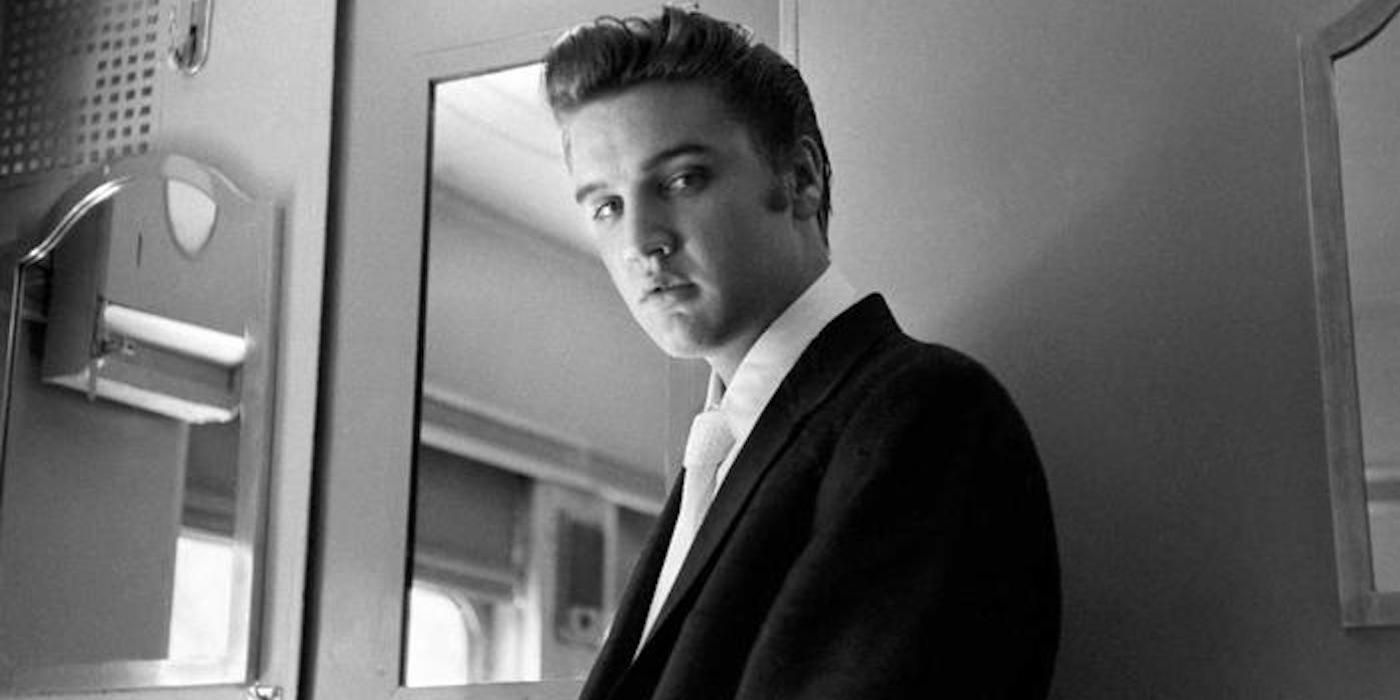Black and white photo of Elvis Presley looking at the camera in his dressing room