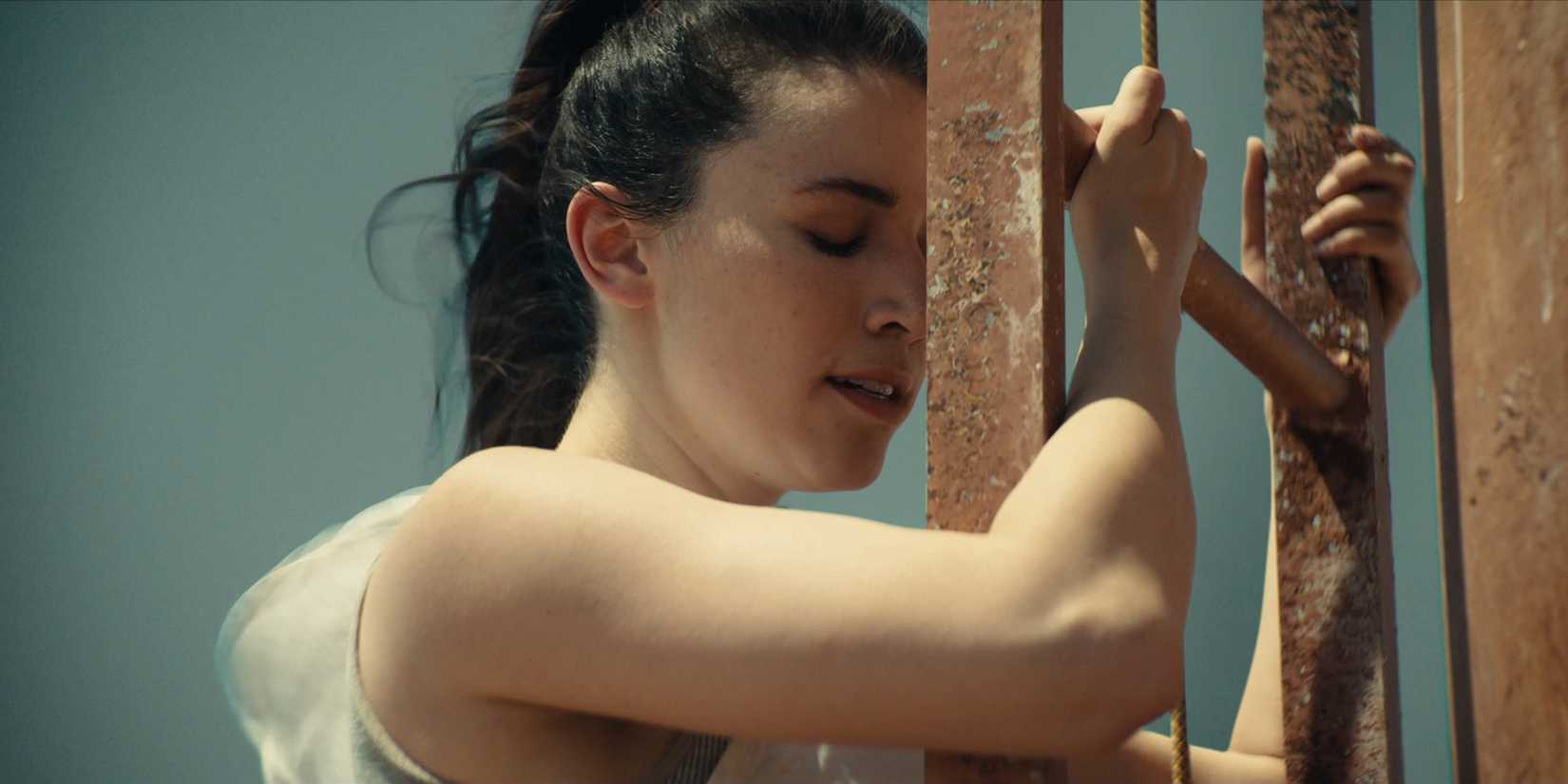 Becky Connor (Grace Caroline Currey) clinging to a ladder with her eyes closed in 2022's Fall