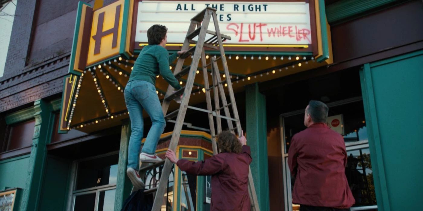 Steve cleans up grafiti on the movie theatre in Stranger Things