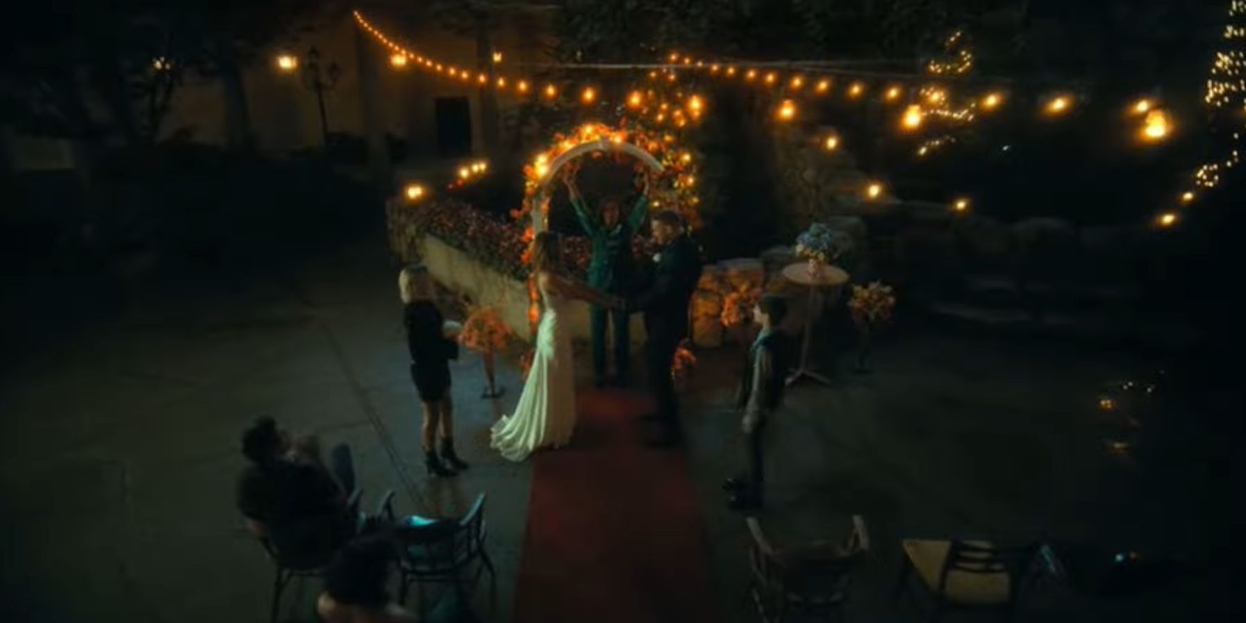 Image of everyone at Sloane and Luther's wedding in the Hotel garden surrounded by hanging lights in The Umbrella Academy