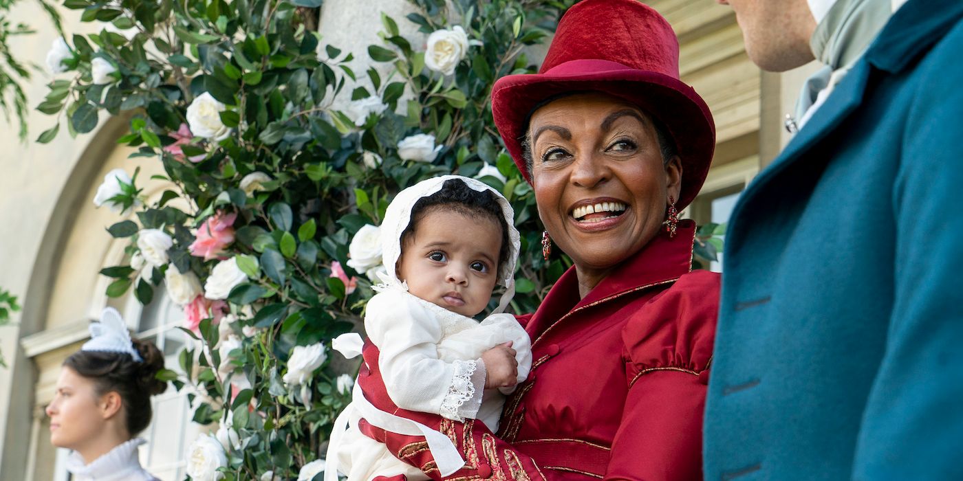 Adjoa Andoh as Lady Danbury holding a baby in Bridgerton