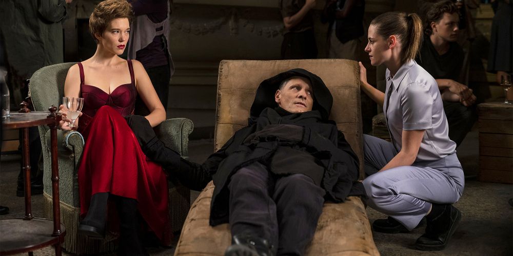 Saul rests on a chair surrounded by two women in Crimes of the Future