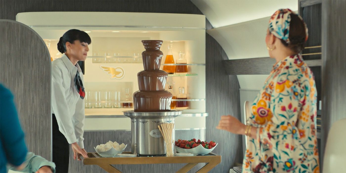 A staff member on Molly's plane on Loot presenting her with a chocolate fountain for guests.