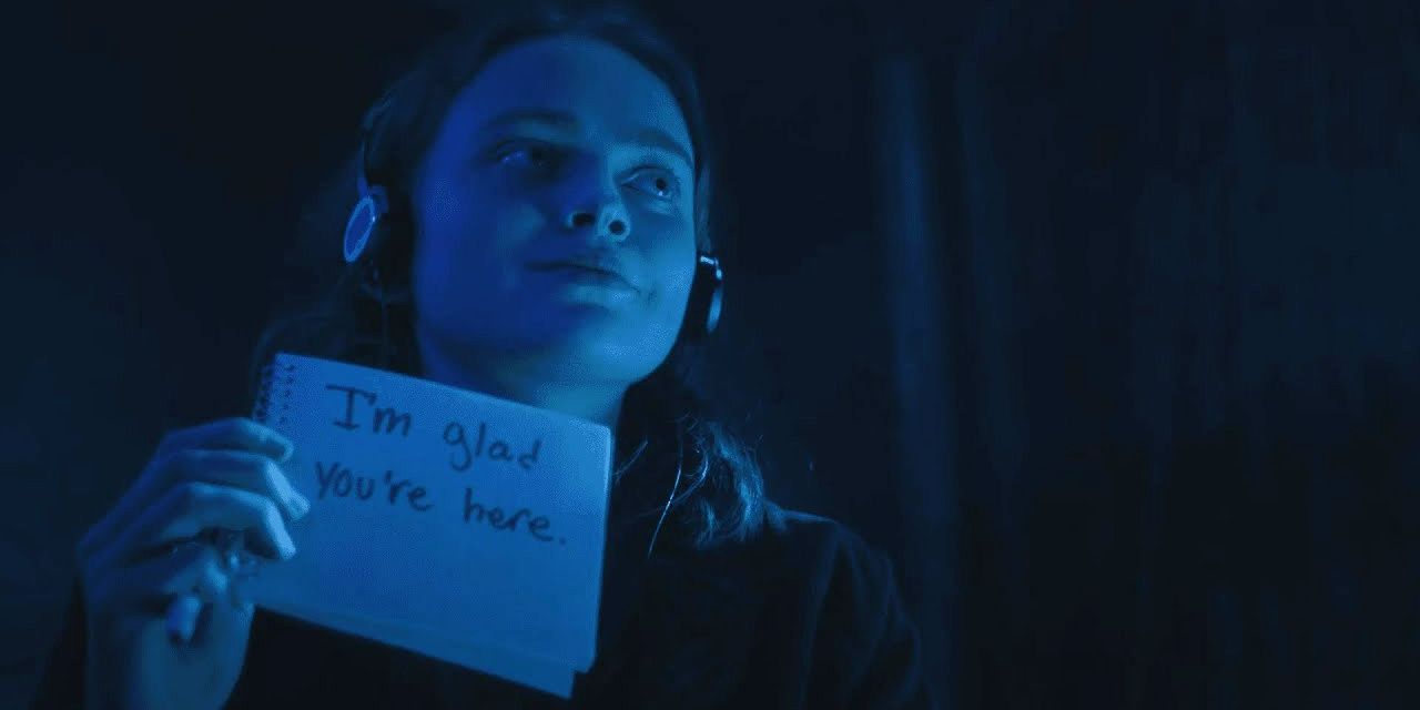 Max wearing headphones holding up a notepad that says &quot;I'm glad you're here.&quot;