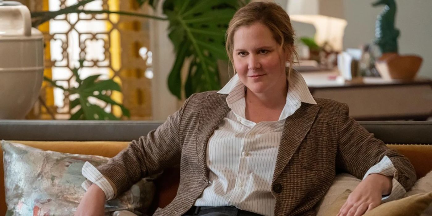 Amy Schumer sitting on her couch smiling in Only Murders in the Building.