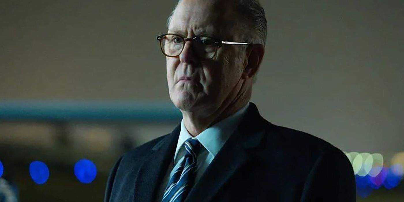 Harold Harper with glasses on in his office, wearing a suit in a scene from The Old Man.