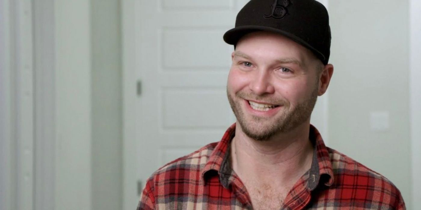 Patrick's brother John Mcmanus from 90 Day Fiancé smiling in red plaid shirt and black hat.
