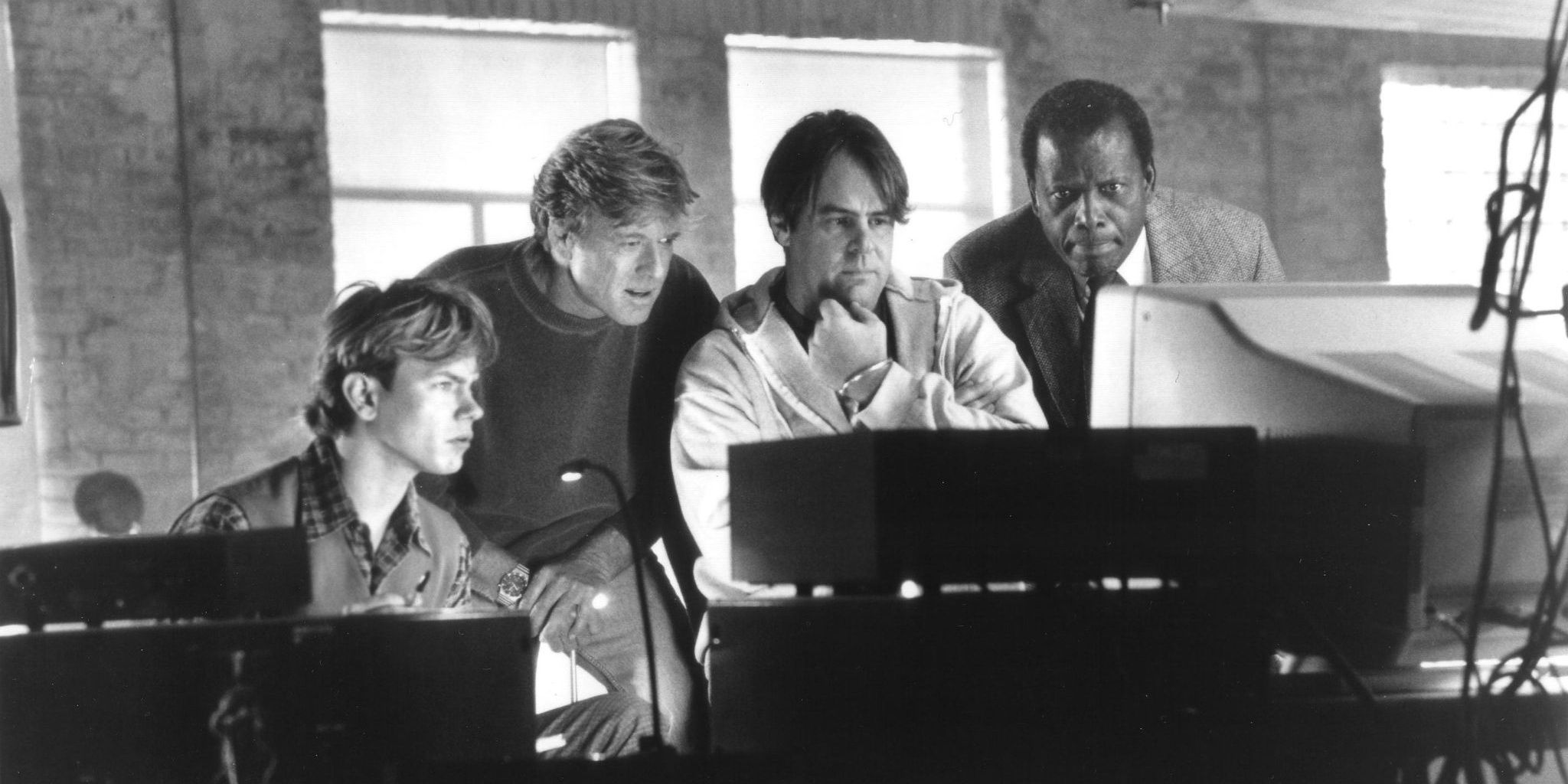 A hacking team headed by Robert Redford peer at a computer screen in Sneakers 1992