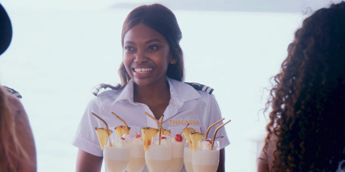 A crew member smiles in front of a tray of drinks from Below Deck Down Under