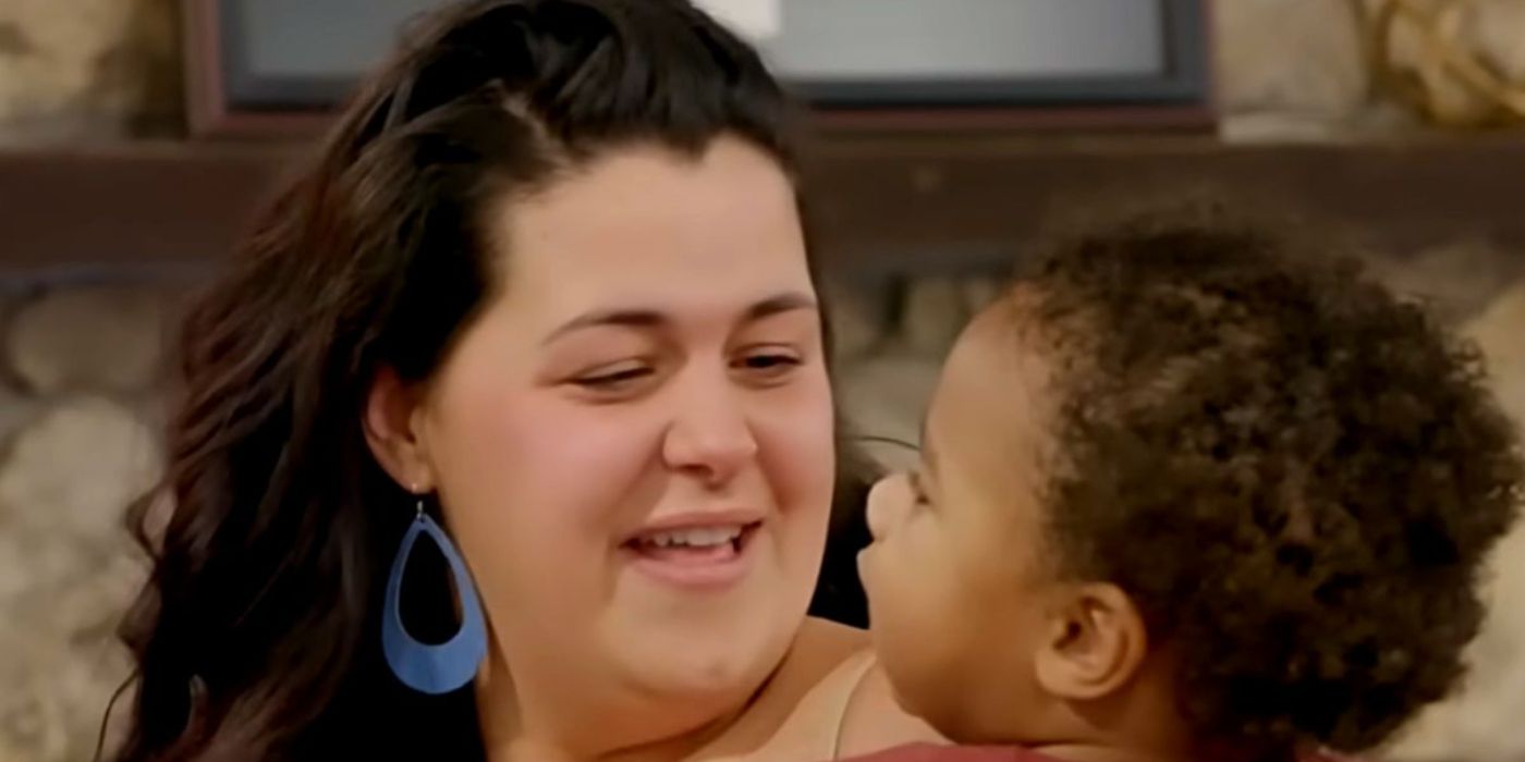 Emily Bieberly with large blue earrings smiling at Koban while holding him on 90 Day Fiancé season 9