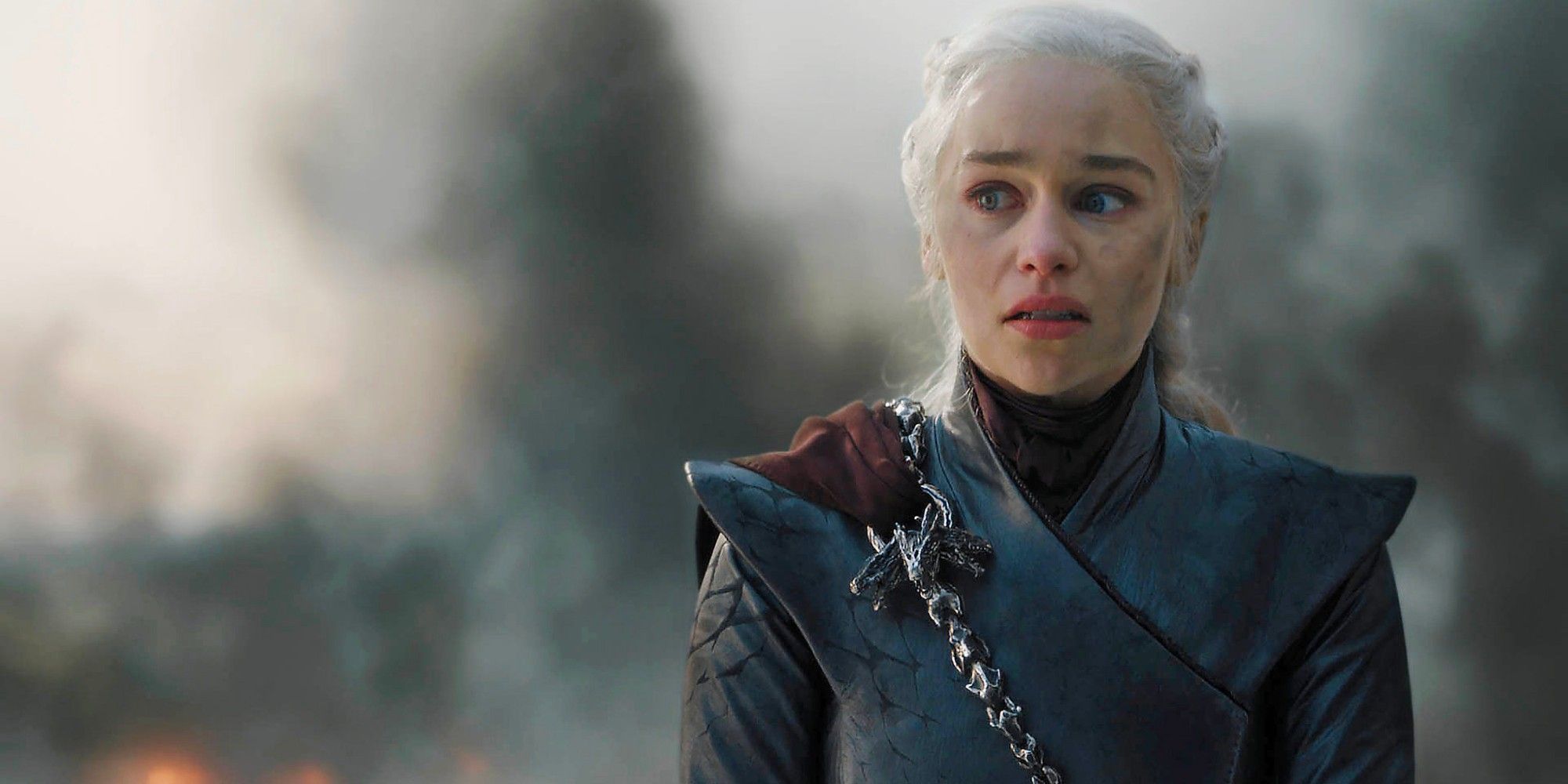 Daenerys Targaryen looking emotional while smoke blows behind her in Game of Thrones.