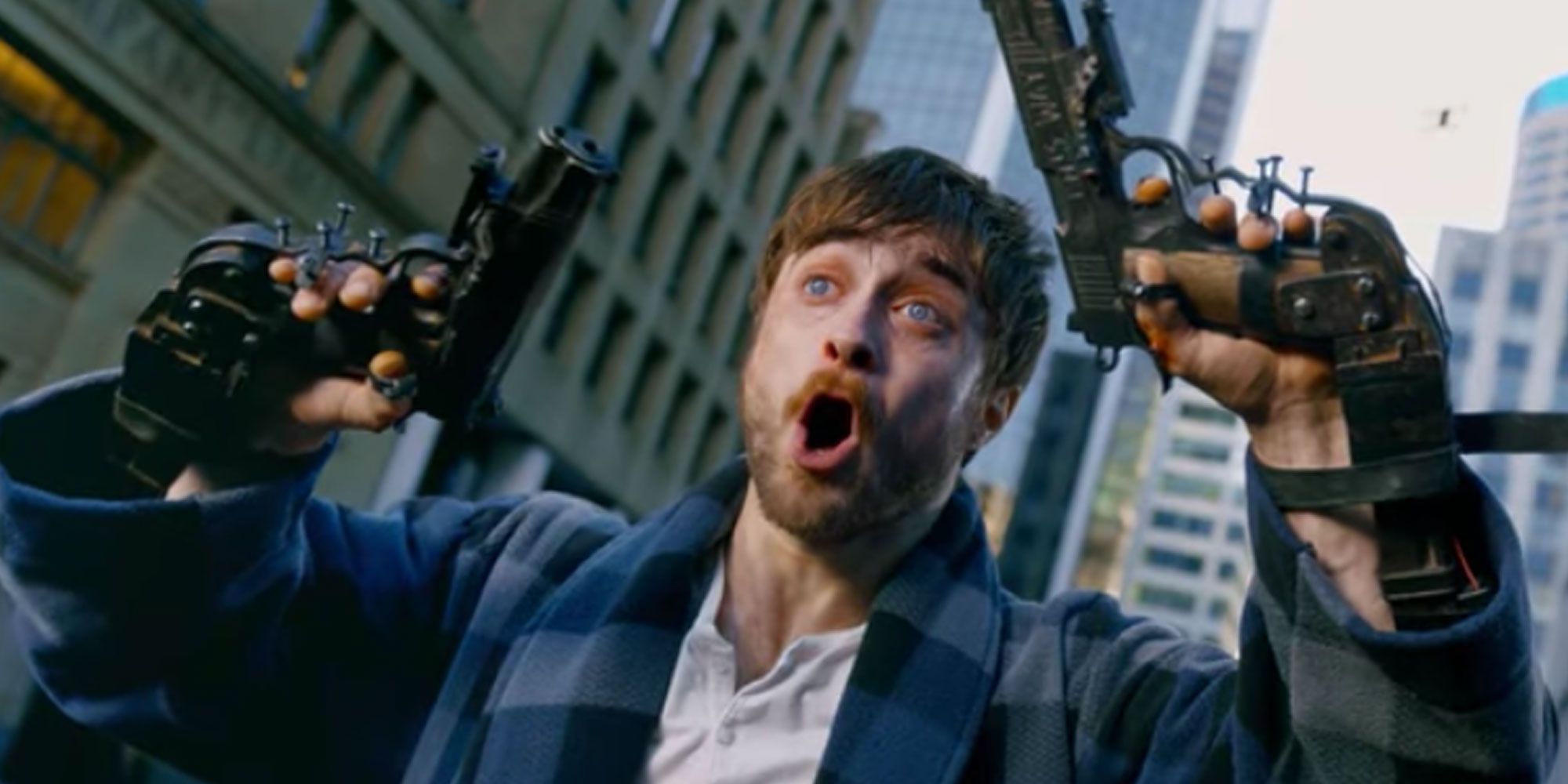 Daniel Radcliffe looking scared with guns attached to his hands in Guns-Akimbo-