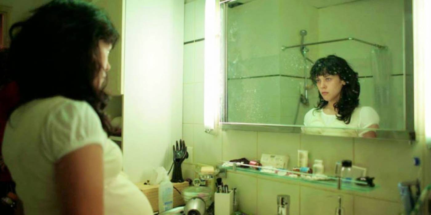Uma mulher grávida olhando no espelho em Inside (2007)