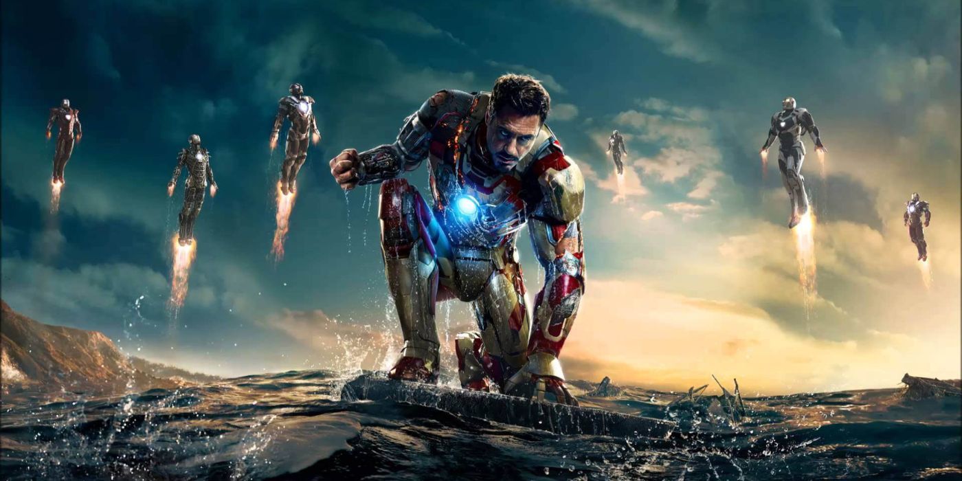 Tony Stark kneeling down while several Iron Man suits fly behind him.