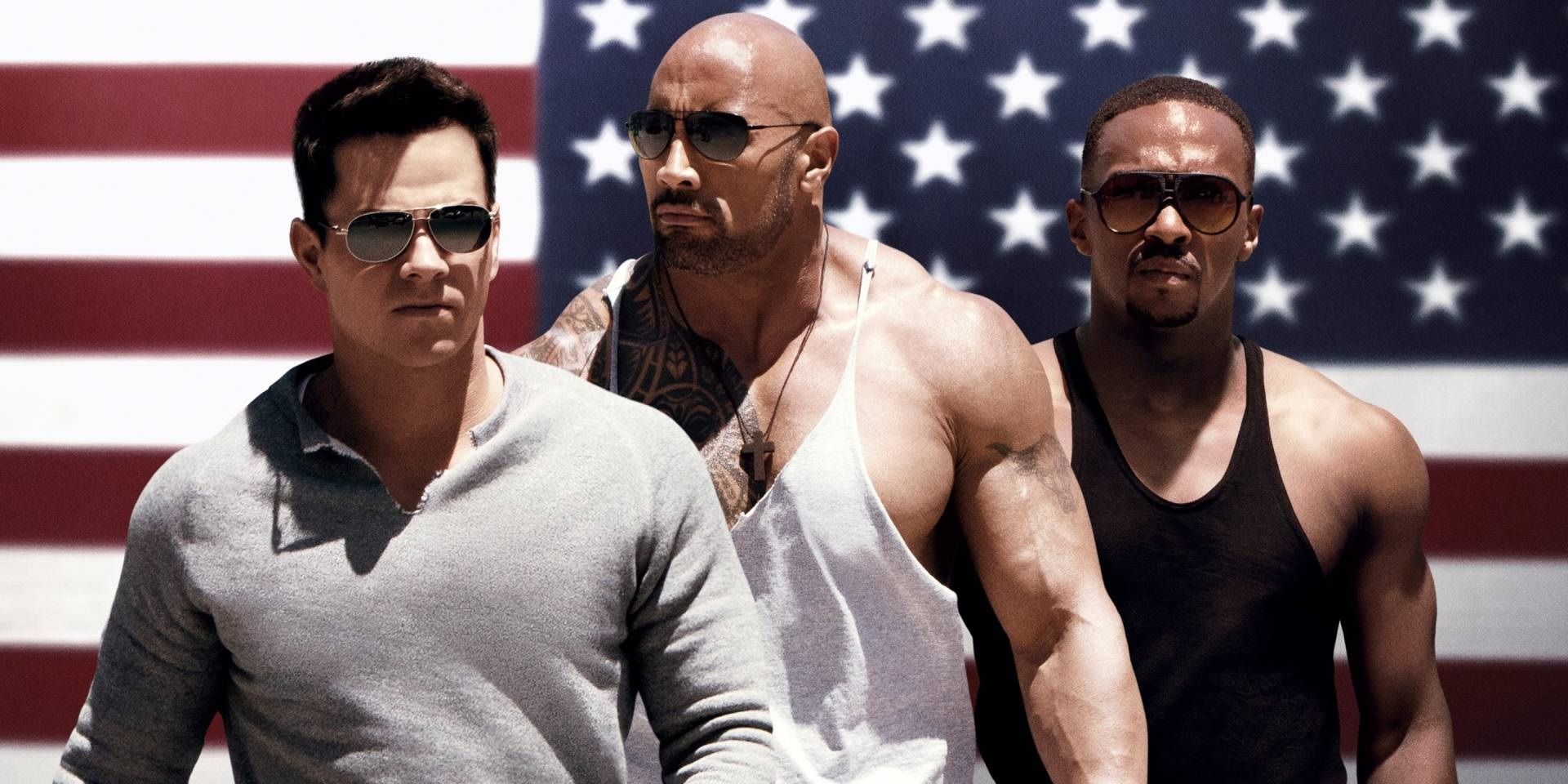 Mark Wahlberg, Dwayne Johnson, and Anthony Mackie in front of an American flag in Pain and Gain