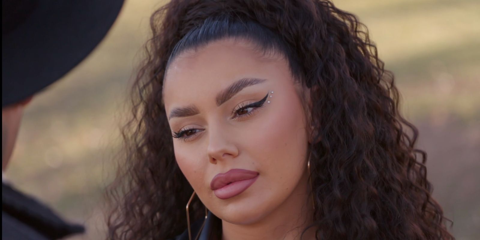 Miona Bell from 90 Day Fiancé season 9 looking serious in curly hair wig