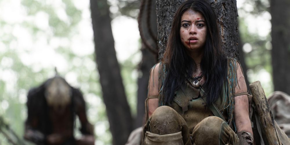 Naru hides from the Predator behind a tree in Prey