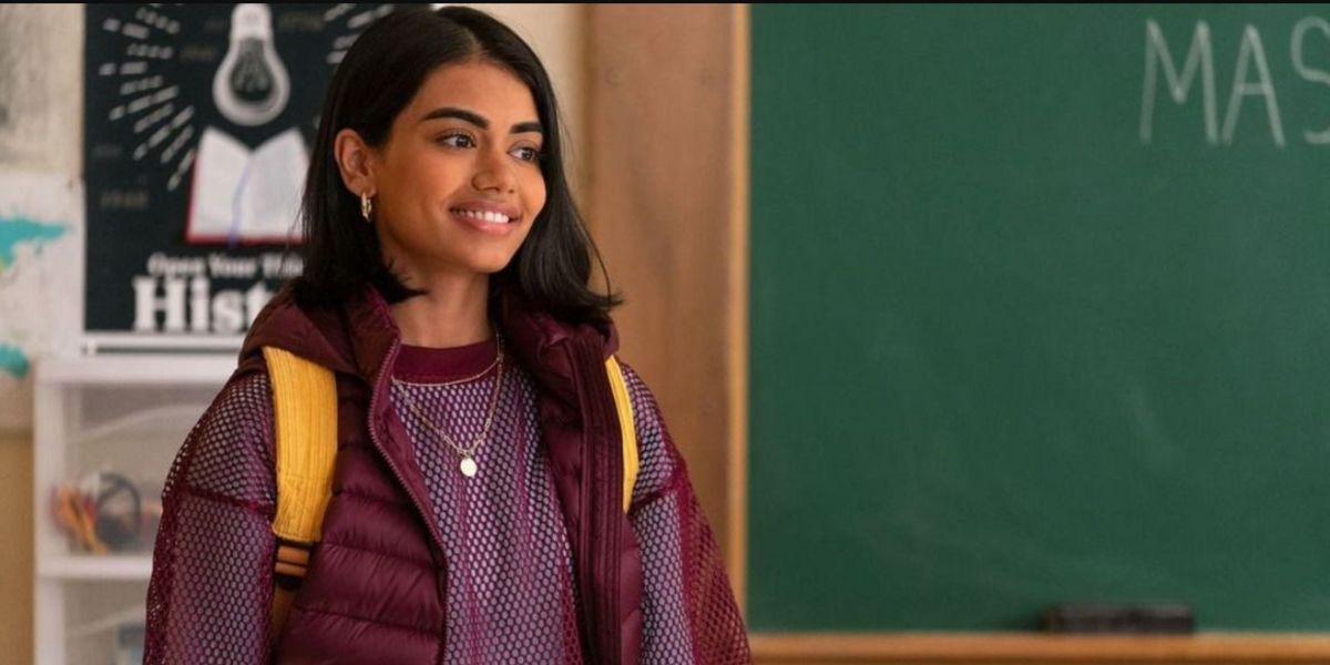 Aneesa smiling while standing in a classroom in Never Have I Ever