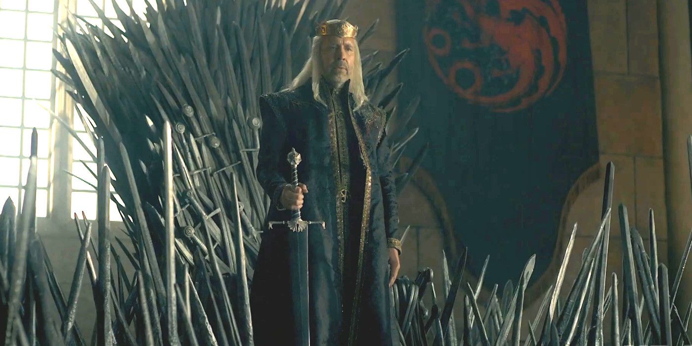 Paddy Considine as King Viserys in House of the Dragon wearing royal robes and a crown standing before a throne made of swords while holding his own sword