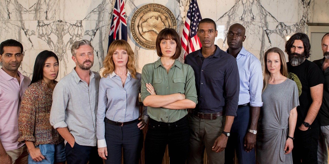 The cast of Pine Gap stands together, ominously staring at the camera