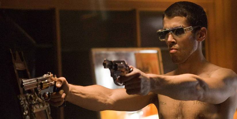 Shirtless man with sunglasses holding two guns in Rocknrolla