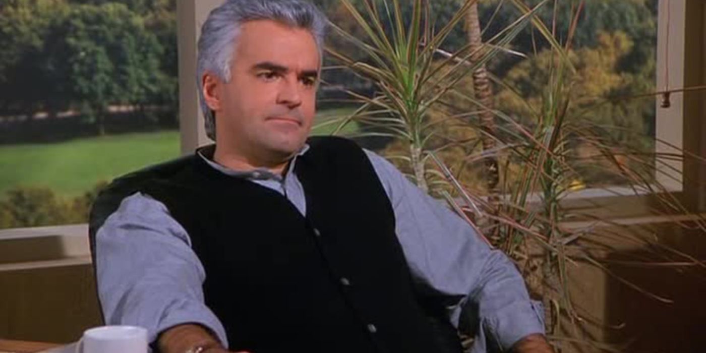 Peterman sitting at his desk with a cup of coffee looking serious on Seinfeld