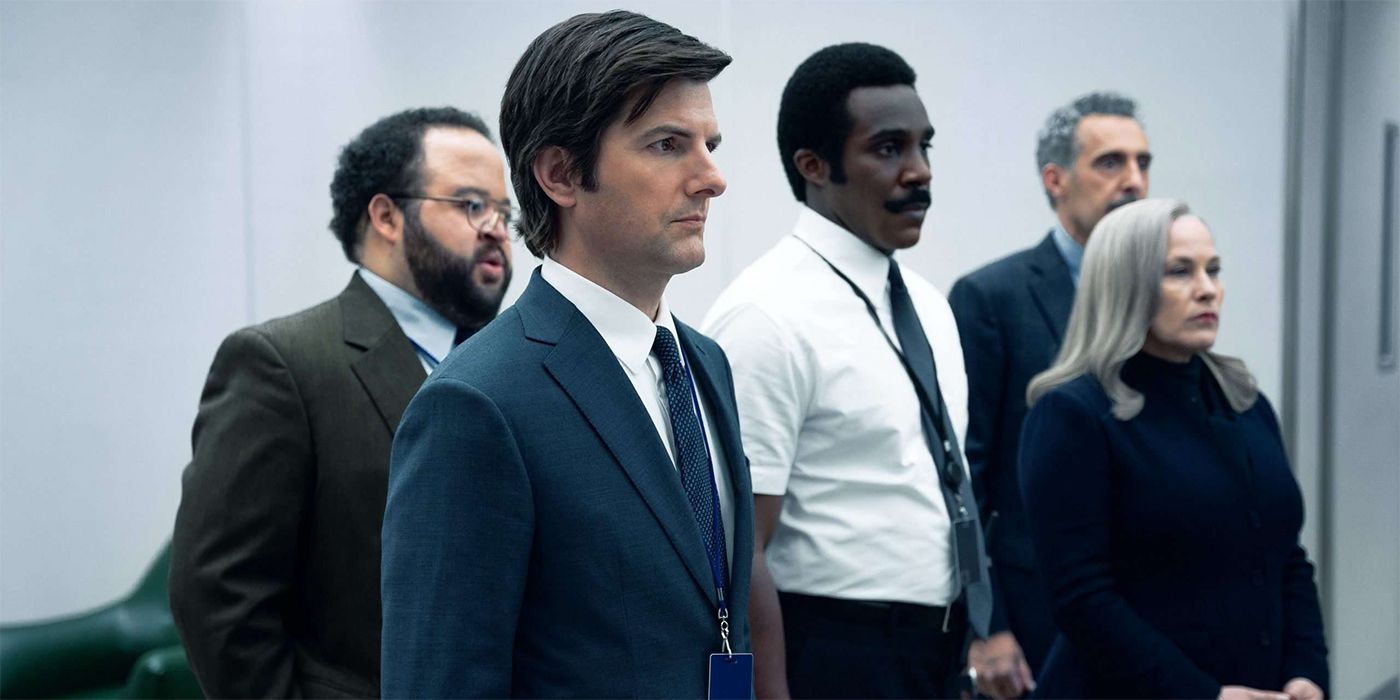 The cast of Severance, standing in a white office in office attire, all looking at something.