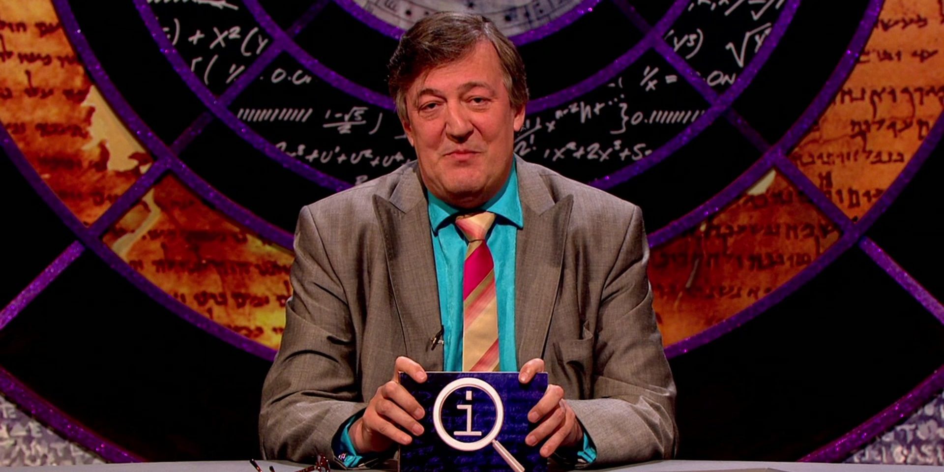 Stephen Fry behind his desk on QI