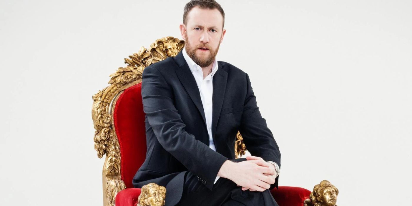 Alex Horne sitting on a red chair in a promo image for Taskmaster
