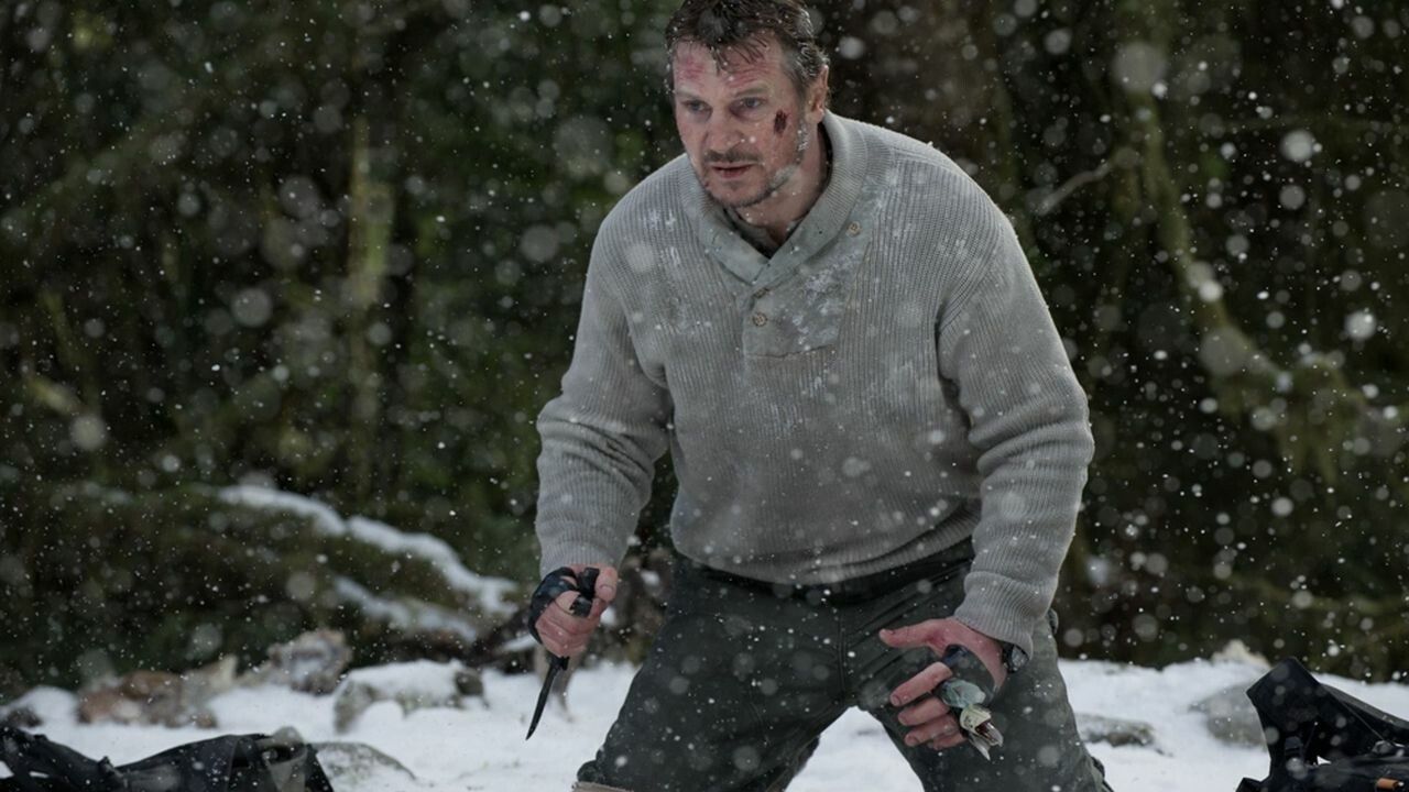 Liam Neeson holding a knife in the snow in The Grey