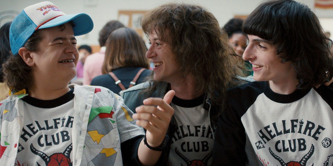 Eddie, Dustin and Mike smiling at each other in Stranger Things.