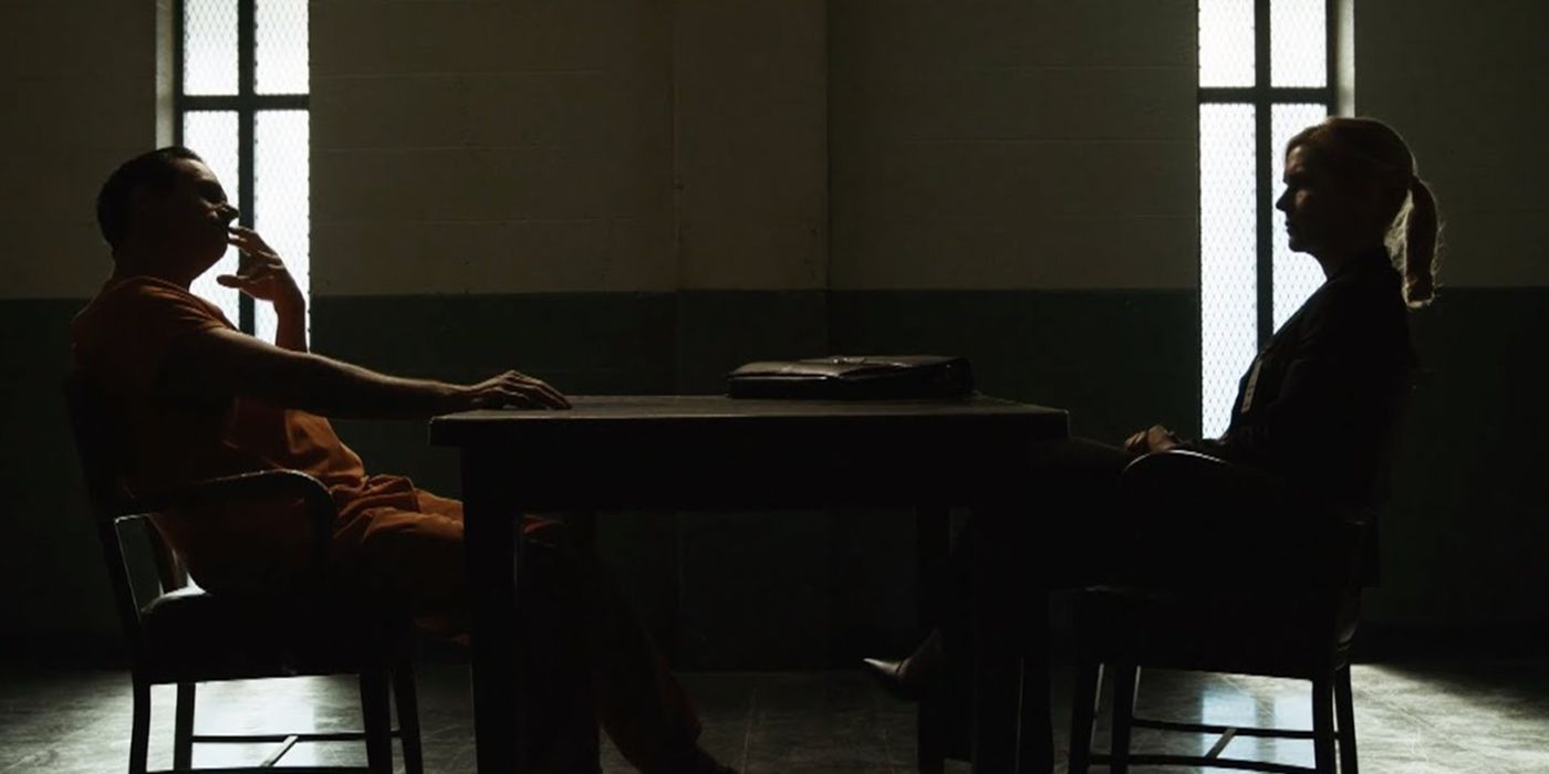 A dark scene with Kim sitting opposite Lalo in jail on Better Call Saul.