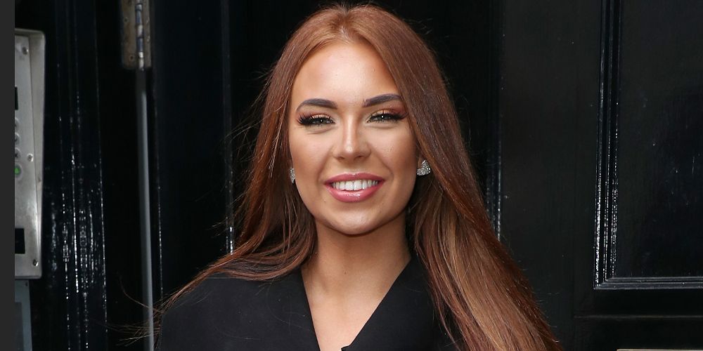 Love Island's Demi stands before a door and smiles