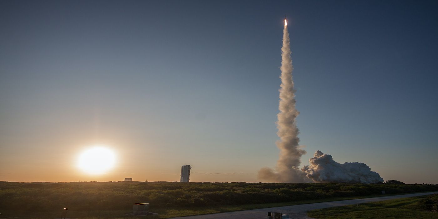 The OSIRIS-REx spacecraft, aboard a ULA Atlas V rocket, races toward its rendezvous with asteroid Bennu as the sun sets in the background.