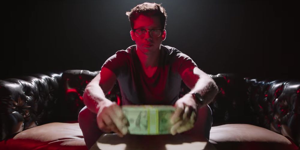 A man holds a brick of cash on a sofa in Generation Hustle