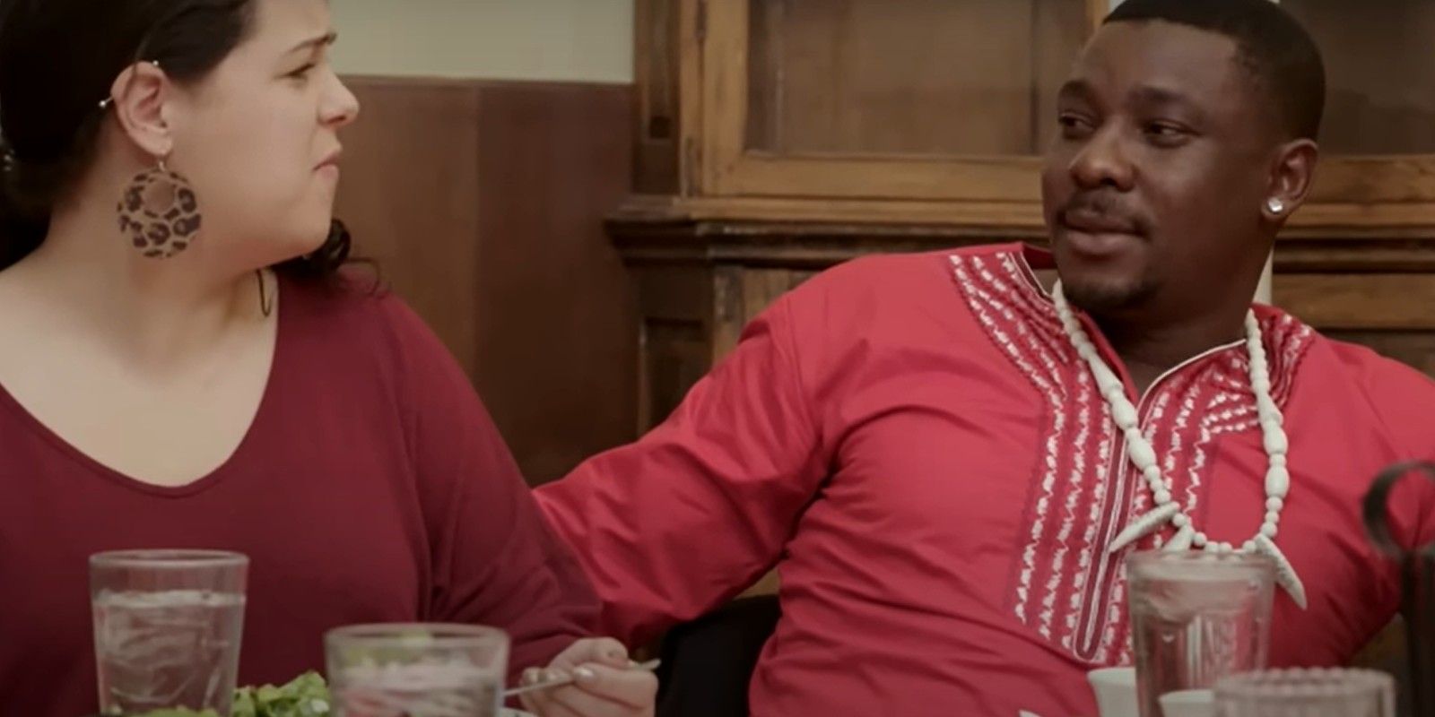 Kobe and Emily from 90 Day Fiancé season 9 at a table with red clothing on